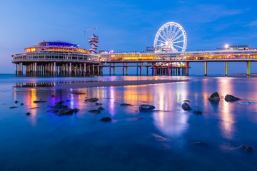 Colorful blue hour sunset on coastline, beach, pier and ferris wheel, Scheveningen, the Hague.