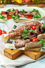 Cold meat snacks. Beautiful serving dishes. Light gray background. Restaurant menu
