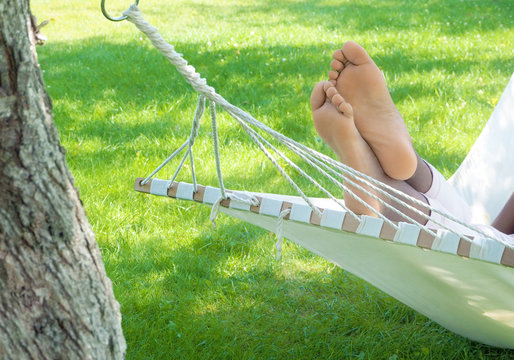 Feet of black woman lying in hammock in a garden