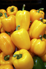 Vertical image of vibrant yellow bell peppers on display at the market