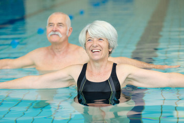 happy senior couple exercising in swimming pool