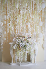 Flower garland on the wall as an element of festive, wedding decor. Light tone. Decorative fireplace.