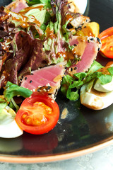 Fototapeta na wymiar Warm Tuna Salad. Beautiful serving dishes. Light gray background. Restaurant menu