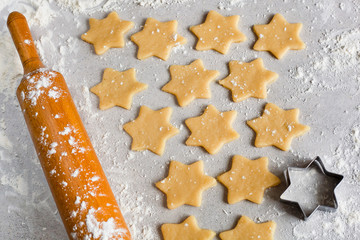 Raw biscuits and a rolling pin with flour on a light gray table. Cutting mold