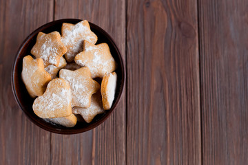 homemade cookies in the shape of hearts and stars on the table in a bowl on a brown wooden background, a place for an inscription