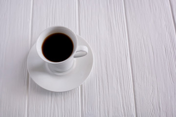 black coffee in a white cup on a white wooden background