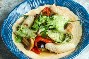 Vegetable salad with squid. Beautiful serving dishes. Light gray background. Restaurant menu