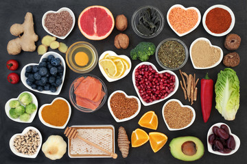 Super food to slow the ageing process concept including fish, fruit, vegetables, herbs, spices, supplement powders honey & dairy on slate. High in antioxidants, anthocyanins, dietary fibre & vitamins.