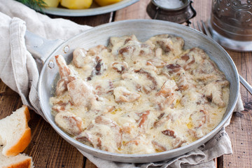 Forest mushrooms in sour cream sauce on a pan on a wooden table, horizontal