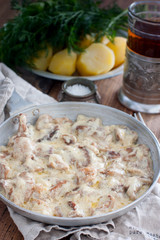Forest mushrooms in sour cream sauce on a frying pan on a wooden table, selective focus