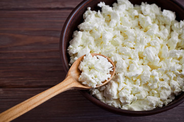 wooden spoon in bowl with homemade curd on a background of brown wooden table, close-up