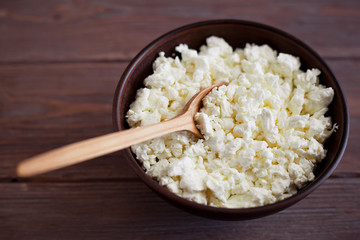 wooden spoon in bowl with homemade curd on a brown wooden table background