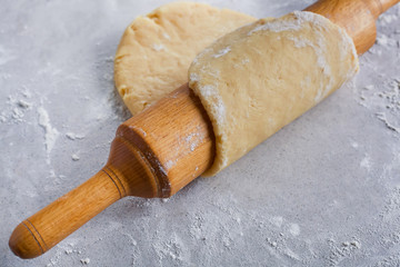 The process of making baking. The test on a rolling pin on a gray table with flour, closeup