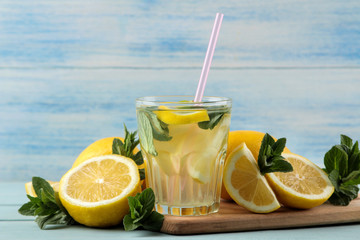 Homemade lemonade with mint and lemon in plastic glasses on a blue wooden background. Refreshing lemonade drink.