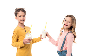 two smiling kids holding milkshakes isolated on white