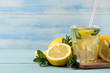 Homemade lemonade with mint and lemon in plastic glasses on a blue wooden background. Refreshing lemonade drink.