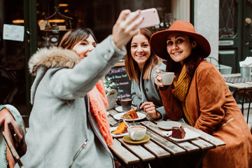 .Group of young friends drinking coffee with cakes in an outdoor cafe in Porto, Portugal. Talking pictures together with their phone. Lifestyle. Travel photography