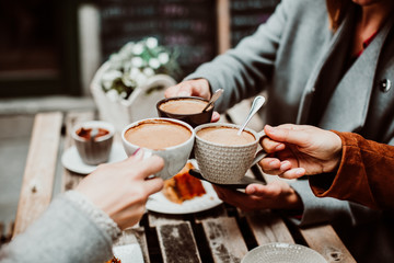 .Group of young friends drinking coffee with cakes in an outdoor cafe in Porto, Portugal. Holding their cups together. Close up. Lifestyle.. - obrazy, fototapety, plakaty