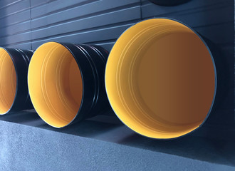 Empty metal barrels attached to a gray wall.