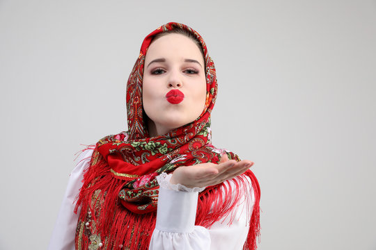Young Russian girl in Russian folk costume in red kiss