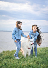 Sisters with a dog on the grass. Friendship concept.