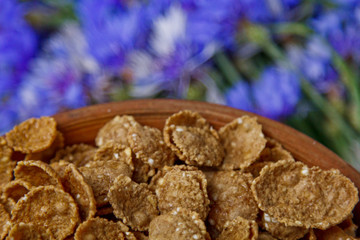 Sugarcorn flakes in a ceramic bowl closeup top view. light breakfast scattered on the table with blue flowers closeup. food fast cooking. healthy food, diet