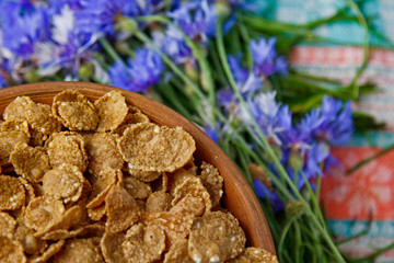 Sugarcorn flakes in a ceramic bowl closeup top view. light breakfast scattered on the table with blue flowers closeup. food fast cooking. healthy food, diet