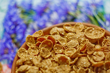 Sugarcorn flakes in a ceramic bowl closeup top view. light breakfast scattered on the table with blue flowers closeup. food fast cooking. healthy food, diet