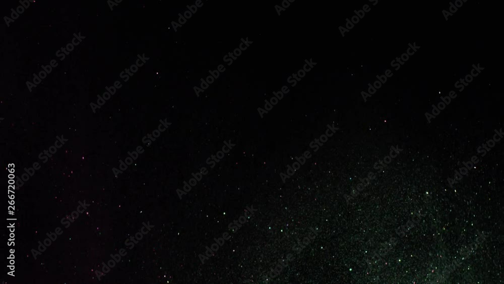 Aufkleber close-up of sparkling colorful particles flying on the black background and shimmering in the dark. 