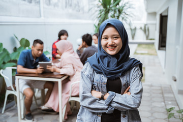 muslim asian woman crossed her arm and looking at camera while friend at the background