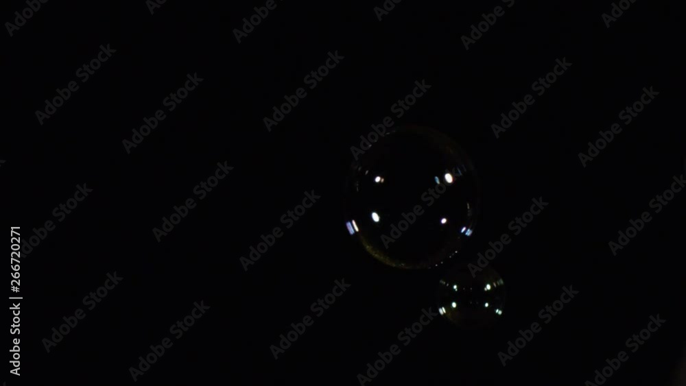 Poster Close-up view of cute soap bubbles floating over the black background and shimmering in the dark. Stock footage. Isolated on black
