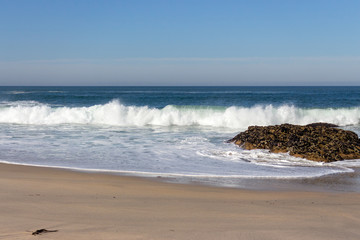 Fototapeta na wymiar Waves crashing on rocks on Atlantic Ocean beach. Scenic seascape. Beautiful surf at seaside. Splashing waves with foam. Travel and vacation on shore. Rocky coastline. Nature power.