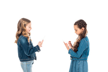 two kids in denim clothes using smartphones isolated on white