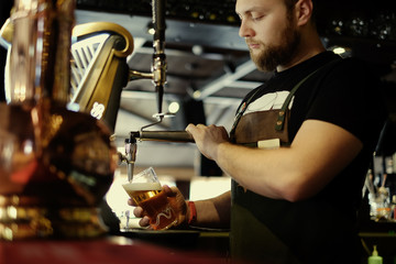 Pouring beer. Cropped image of smiley bartender poring beer to the mug