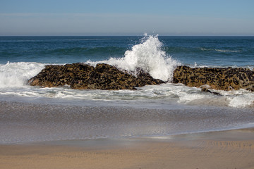 Waves crashing on rocks on Atlantic Ocean beach. Scenic seascape. Beautiful surf at seaside. Splashing waves with foam. Travel and vacation on shore. Rocky coastline. Nature power.