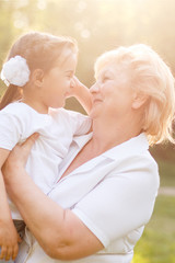 Grandmother hugging granddaughter legs and smiling.
