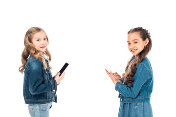 two kids in denim clothes using smartphones isolated on white