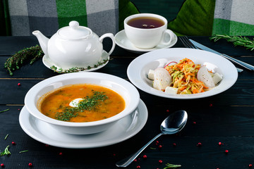 Traditional Russian soup Solyanka cooked with meat, sausages, salted cucumbers and olives. White casserole on the wooden table.