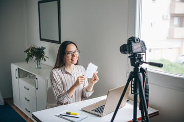 Girl video blogger or online foreign language teacher writes a training video for their subscribers...