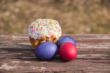 painted eggs and cake on a wooden table in Sunny color
