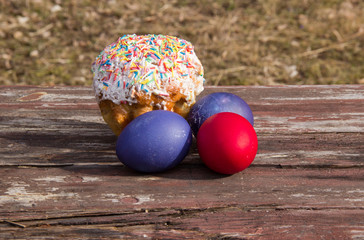 painted eggs and cake on a wooden table in Sunny color