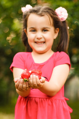 Little girl is carrying a basket of strawberries