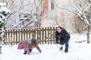 Young man woman couple playing making snowballs in winter snowstorm snowing at house garden front...