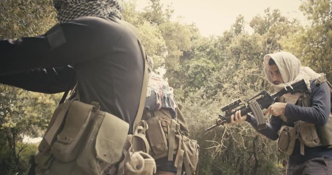 Squad of armed terrorists patrolling a forest area during combat