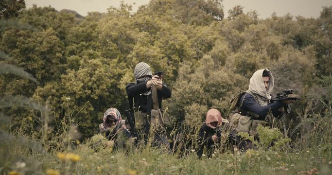 Squad of armed terrorists patrolling a forest area during combat