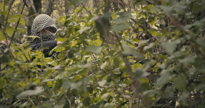Squad of armed terrorists patrolling a forest area during combat