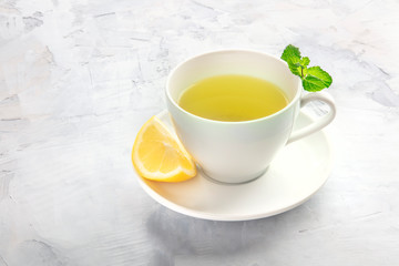 Obraz na płótnie Canvas An angle view of a cup of tea with a slice of lemon and mint leaves, with a place for text