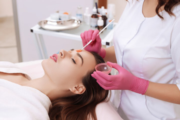 Young woman cleaning face skin in salon.