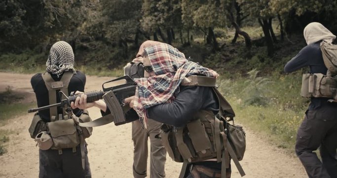 Squad of armed terrorists patrolling a forest area during combat