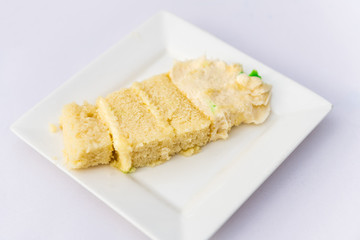 Restaurant or wedding reception white table with one plate and vanilla cream cake slice closeup